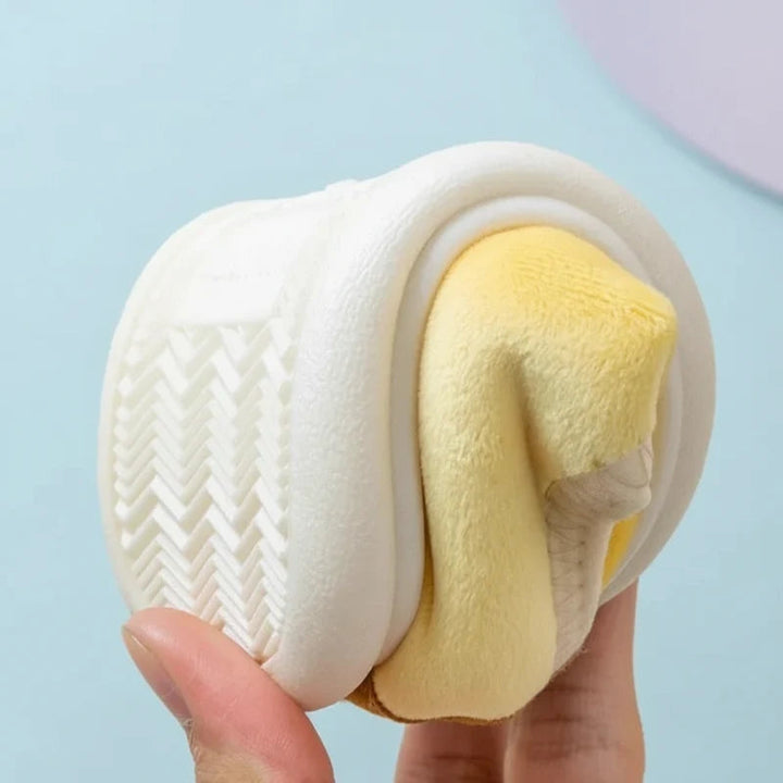 Yellow slipper bent to show its flexible white sole and chevron-patterned tread