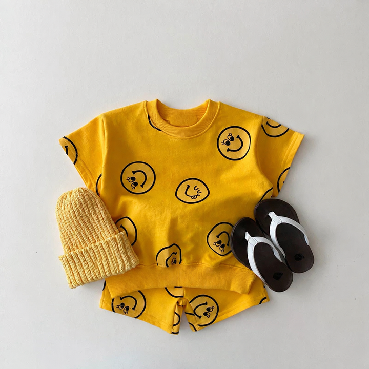 Yellow smiley-print T-shirt and shorts set styled with a knit hat and black sandals