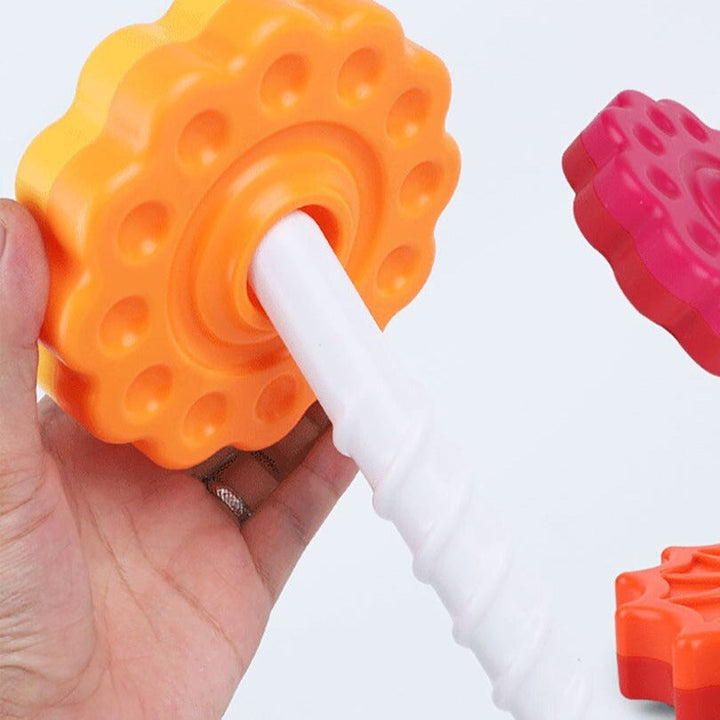 Hand holding a yellow stacking disc around the white spiral post